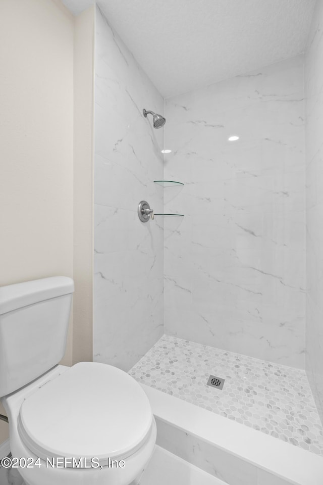 bathroom with a tile shower and toilet