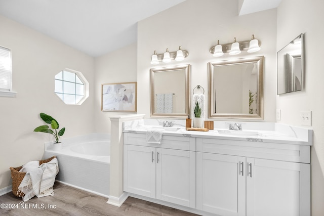 bathroom with vanity, a relaxing tiled tub, and wood-type flooring