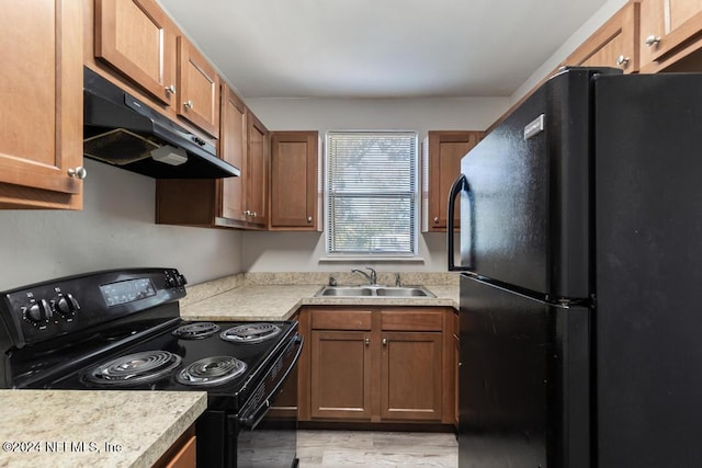 kitchen with black appliances, sink, and light hardwood / wood-style flooring