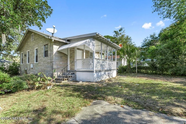 view of side of property featuring covered porch and a yard