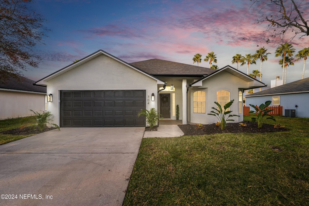 ranch-style home featuring a lawn, central AC unit, and a garage