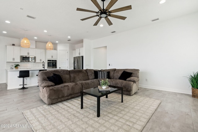 living room with ceiling fan, light hardwood / wood-style floors, and sink