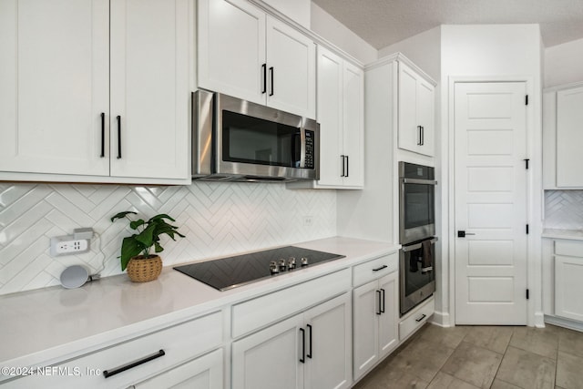 kitchen with backsplash, light tile patterned flooring, white cabinetry, and stainless steel appliances