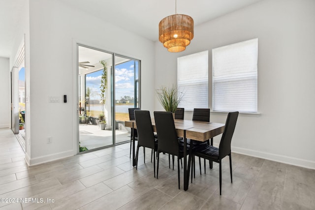 dining area with light wood-type flooring, a water view, and ceiling fan