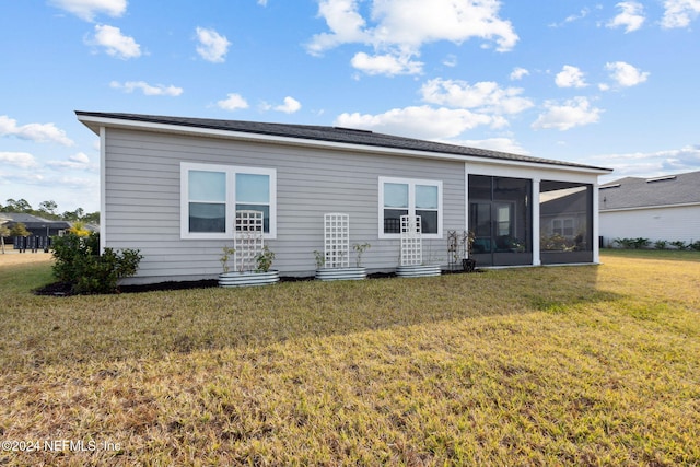 back of property with a lawn and a sunroom