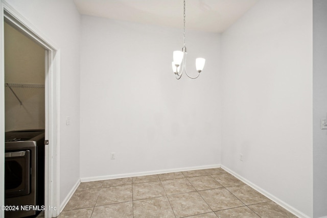 unfurnished dining area with an inviting chandelier, light tile patterned floors, and washer / dryer