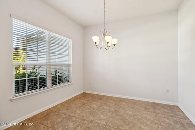 tiled spare room featuring a notable chandelier