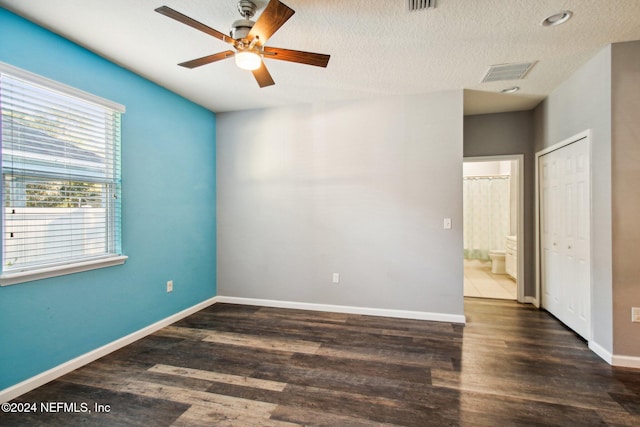 empty room featuring ceiling fan, dark wood-type flooring, and a textured ceiling