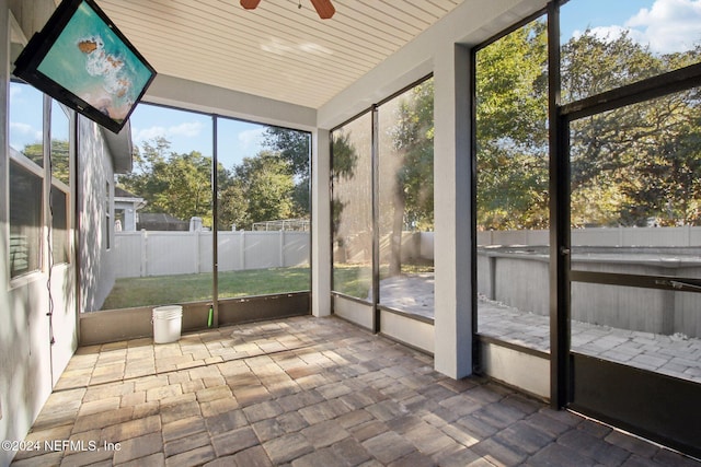 unfurnished sunroom featuring ceiling fan and a healthy amount of sunlight