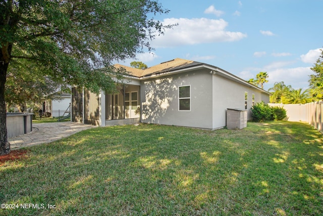 rear view of property featuring a sunroom and a lawn