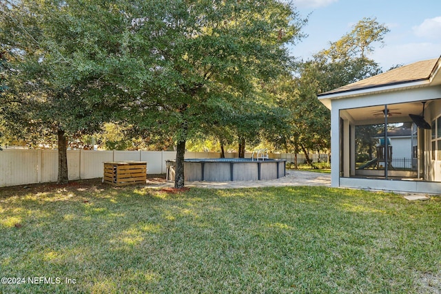 view of yard featuring ceiling fan and a fenced in pool