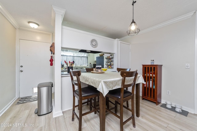 dining room with light hardwood / wood-style floors, a textured ceiling, and ornamental molding