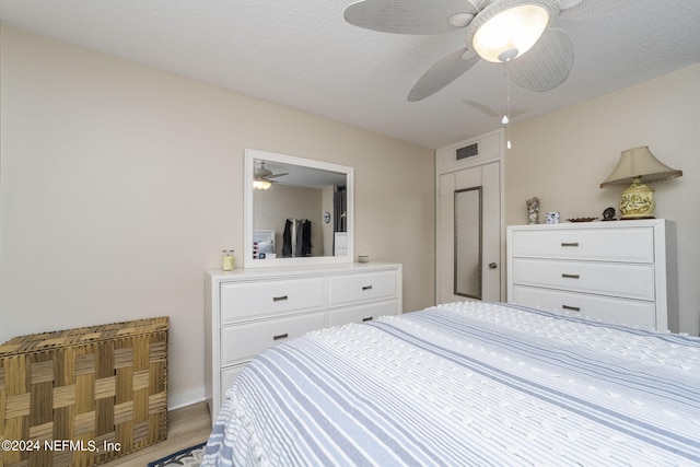 bedroom featuring hardwood / wood-style floors, ceiling fan, and a textured ceiling