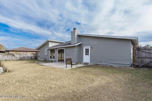 back of house with a lawn and a patio area