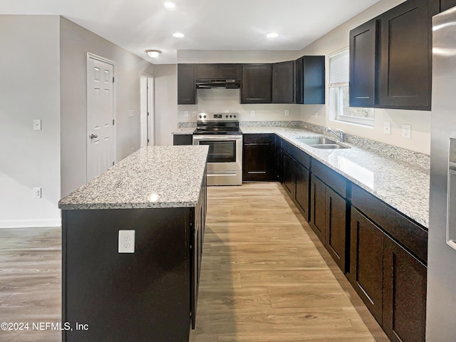 kitchen featuring appliances with stainless steel finishes, light stone counters, sink, light hardwood / wood-style flooring, and a kitchen island