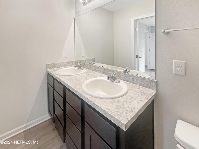 bathroom featuring wood-type flooring, vanity, and toilet