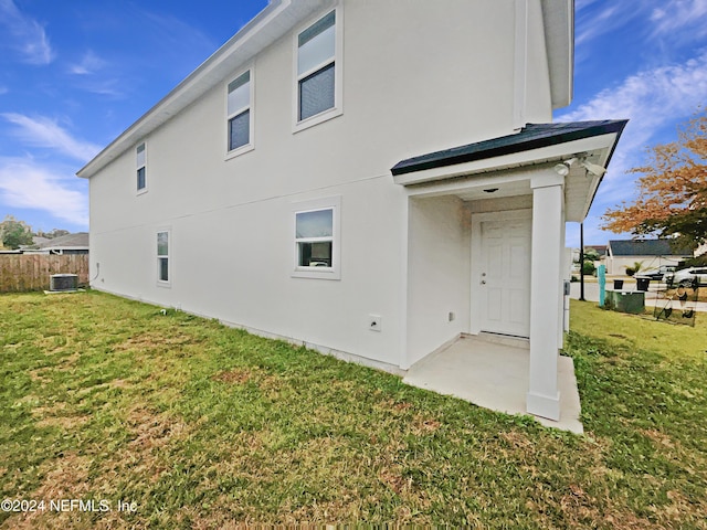 rear view of property with a lawn and central AC unit