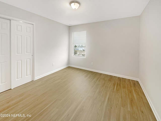 unfurnished bedroom with light wood-type flooring and a closet