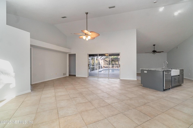 unfurnished living room with ceiling fan, light tile patterned flooring, sink, and high vaulted ceiling