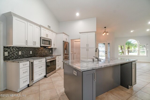 kitchen featuring white cabinets, appliances with stainless steel finishes, tasteful backsplash, and a kitchen island with sink