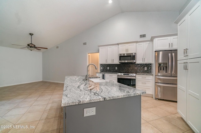 kitchen with white cabinets, appliances with stainless steel finishes, a kitchen island with sink, and sink