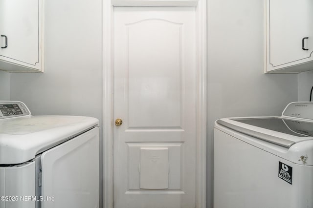 clothes washing area featuring washer and clothes dryer and cabinets