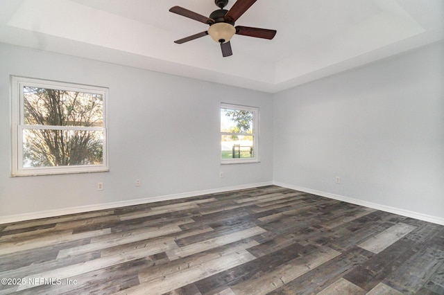 spare room featuring dark hardwood / wood-style flooring, a raised ceiling, and ceiling fan