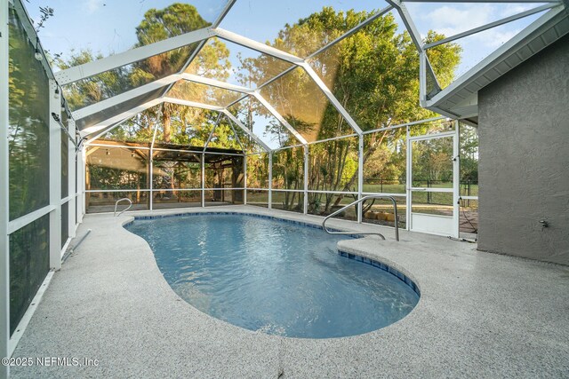 view of pool with glass enclosure and a patio area