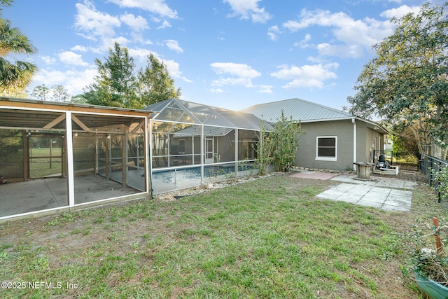 rear view of house featuring a lawn, glass enclosure, and a patio area