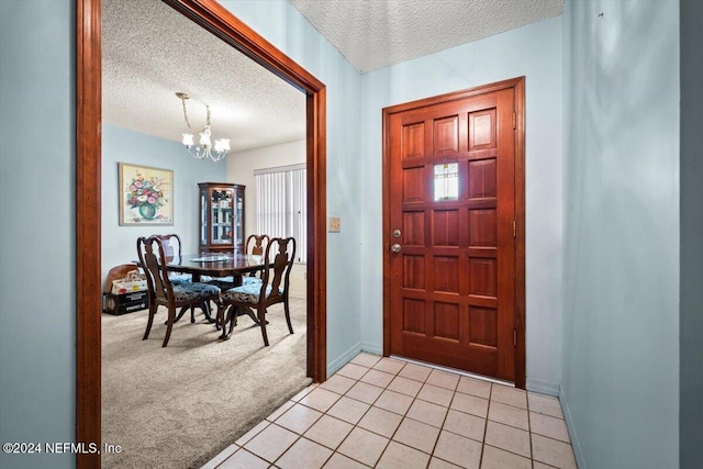 entryway with light colored carpet, a textured ceiling, and a chandelier