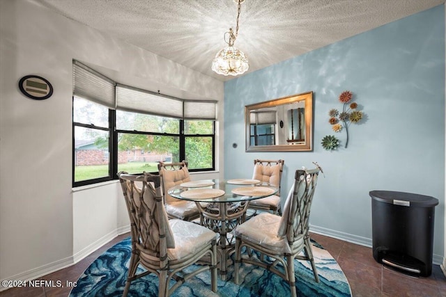 dining space featuring dark tile patterned floors, a healthy amount of sunlight, a textured ceiling, and a notable chandelier