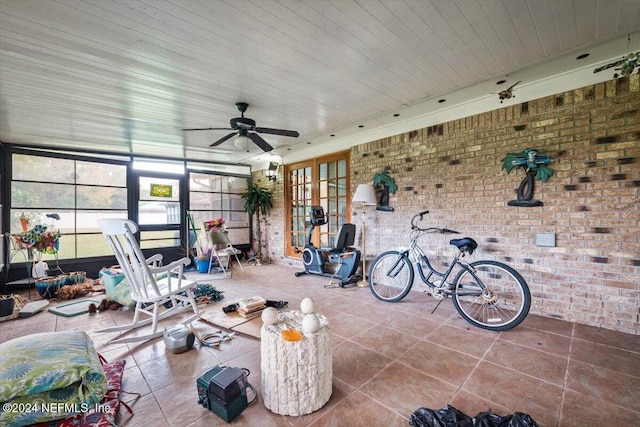 interior space with tile patterned floors, ceiling fan, french doors, and brick wall