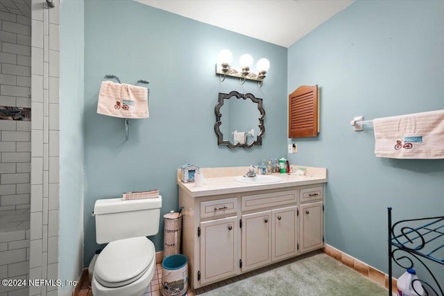 bathroom with tile patterned floors, vanity, toilet, and a tile shower