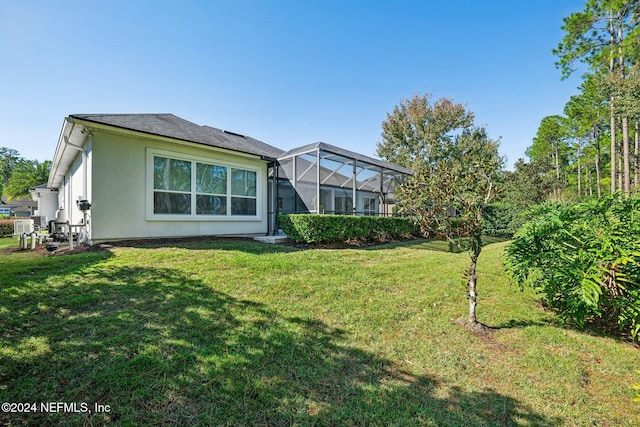 rear view of house with a yard and glass enclosure