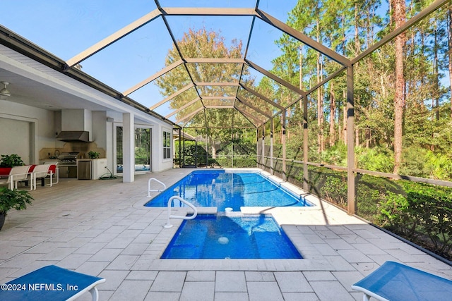 view of swimming pool featuring a patio, an outdoor kitchen, and a lanai