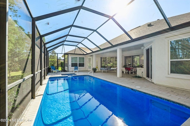 view of swimming pool featuring outdoor lounge area, a patio area, and glass enclosure