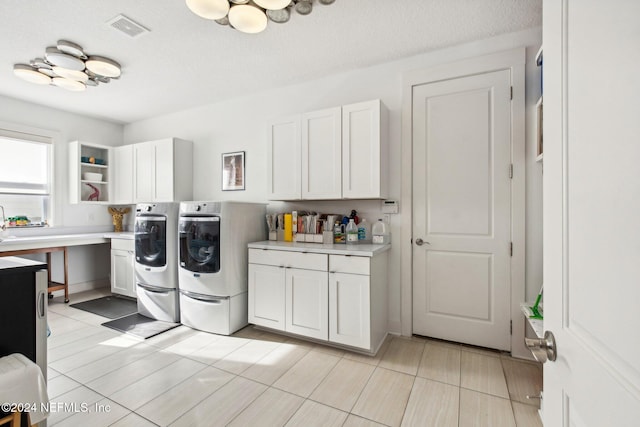 washroom featuring cabinets, a textured ceiling, and independent washer and dryer