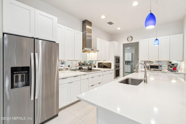 kitchen with wall chimney exhaust hood, sink, appliances with stainless steel finishes, pendant lighting, and white cabinets