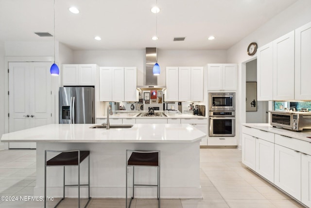 kitchen featuring sink, appliances with stainless steel finishes, pendant lighting, range hood, and white cabinets