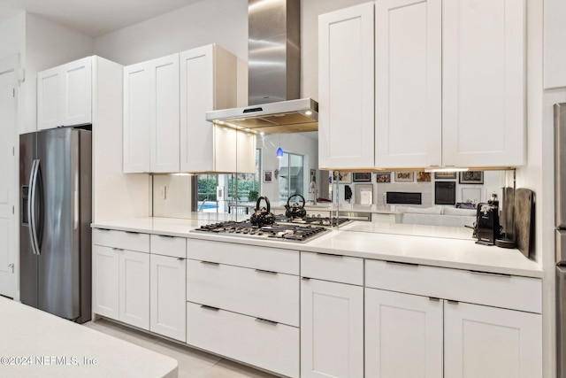 kitchen featuring wall chimney exhaust hood, white cabinetry, and stainless steel appliances