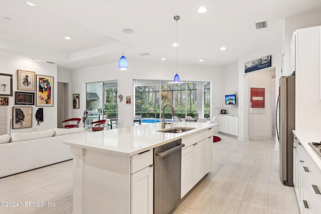 kitchen with sink, a center island with sink, pendant lighting, stainless steel appliances, and white cabinets