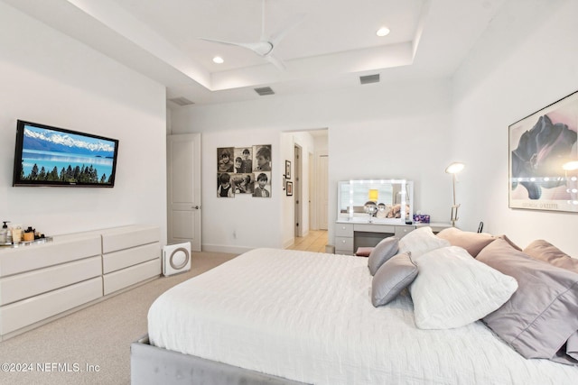 carpeted bedroom with ceiling fan and a raised ceiling