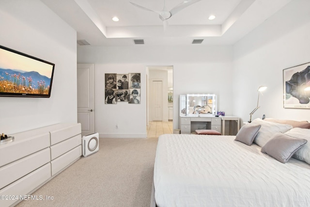 bedroom with ceiling fan, a tray ceiling, and light carpet