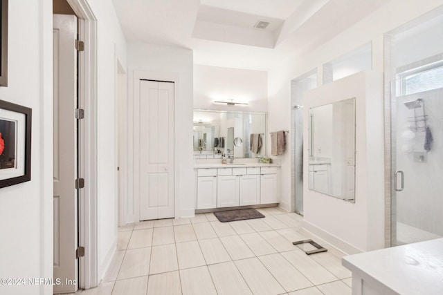 bathroom with a shower with door, vanity, a raised ceiling, and tile patterned flooring