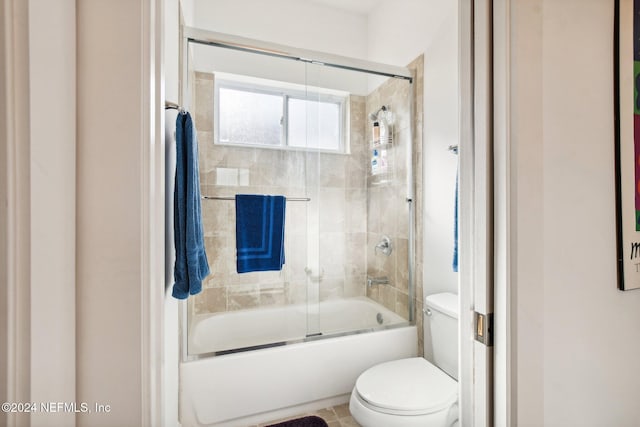 bathroom featuring bath / shower combo with glass door and toilet