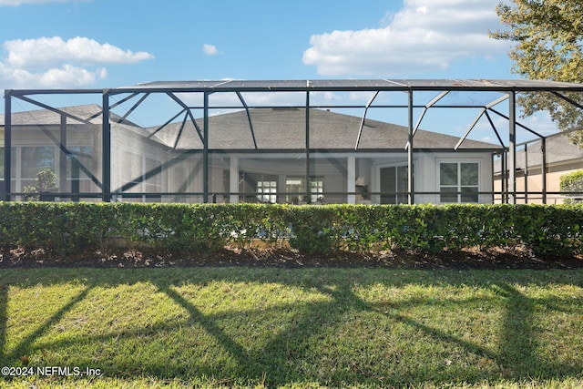 rear view of property with a yard and glass enclosure