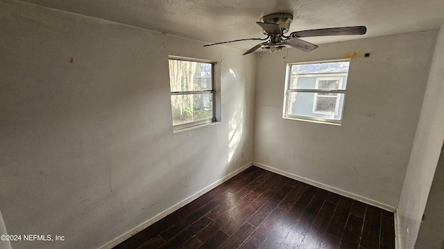 unfurnished room with a textured ceiling, dark hardwood / wood-style floors, a wealth of natural light, and ceiling fan