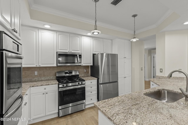 kitchen featuring stainless steel appliances, a sink, white cabinetry, light stone countertops, and pendant lighting