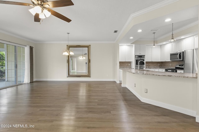 kitchen with light stone counters, pendant lighting, appliances with stainless steel finishes, ornamental molding, and white cabinetry