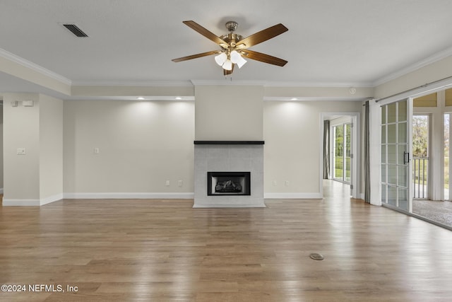 unfurnished living room with light wood finished floors, ornamental molding, a fireplace, and visible vents